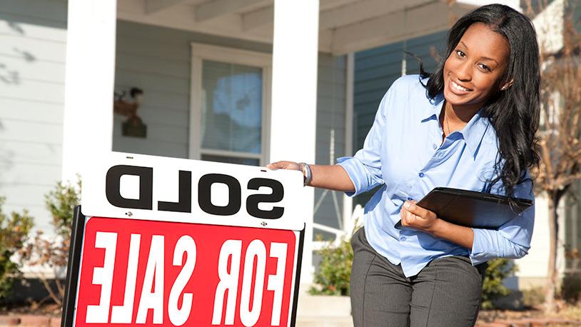 Realtor in front of house with sold sign
